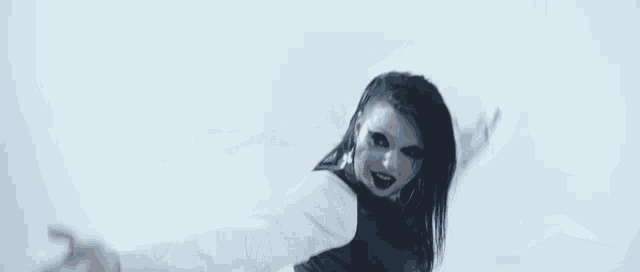 a woman in a white dress and black vest is dancing on a checkerboard floor .