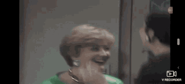 a woman in a green shirt is laughing in front of a man .