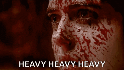 a close up of a person 's face with blood on it and the words `` heavy heavy heavy '' written below it .