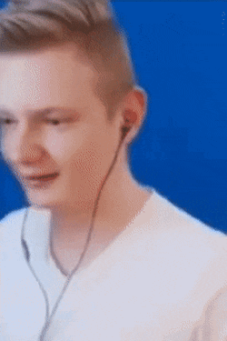 a man wearing earbuds is smiling in front of a blue background .