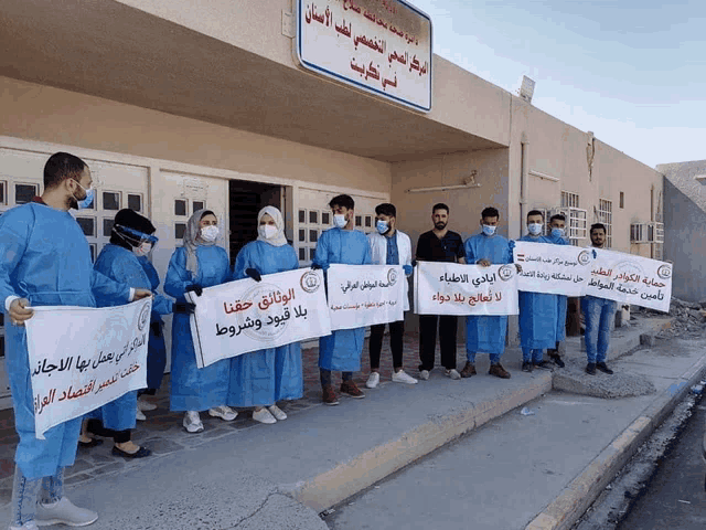 a group of people holding signs in front of a building with arabic writing on it