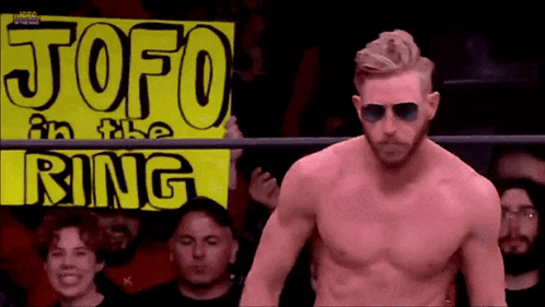 a man in a wrestling ring is holding a sign that says `` jofo in the ring '' .