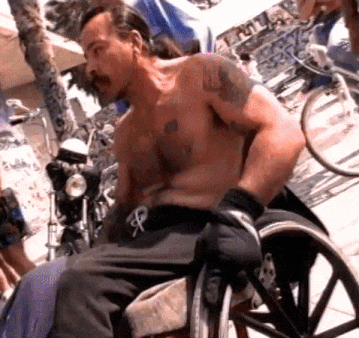 a shirtless man in a wheelchair has a tattoo on his arm