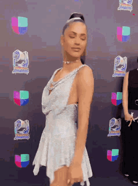 a woman in a white dress is standing in front of a wall that says ' awards ' on it