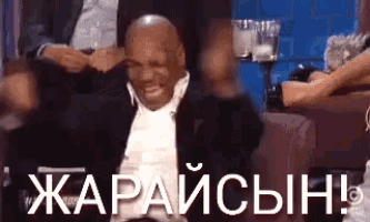 a man in a suit is sitting in a chair with his arms in the air and a woman sitting next to him .