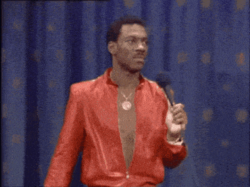 a man in a red jacket is holding a microphone and saying " you gotta be a horny motherfucker "