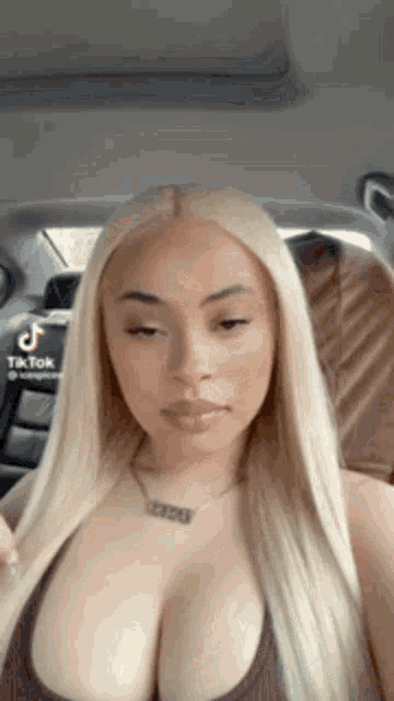 a woman with blonde hair is sitting in a car wearing a necklace .