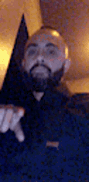 a man with a beard is pointing his finger at the camera in a blurry photo .