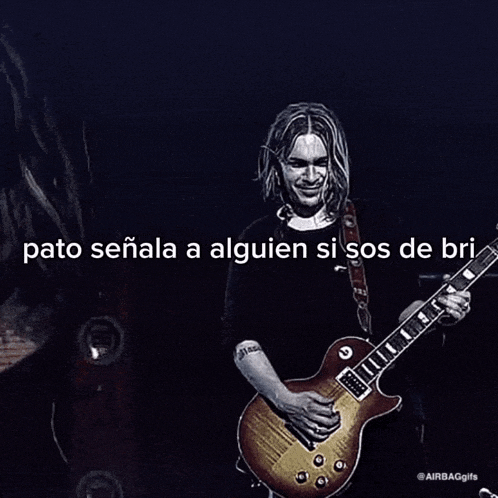a man with long hair is playing a guitar on a stage