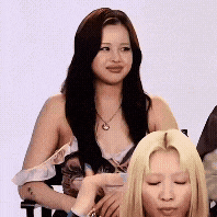 a woman with long black hair is sitting next to another woman with blonde hair