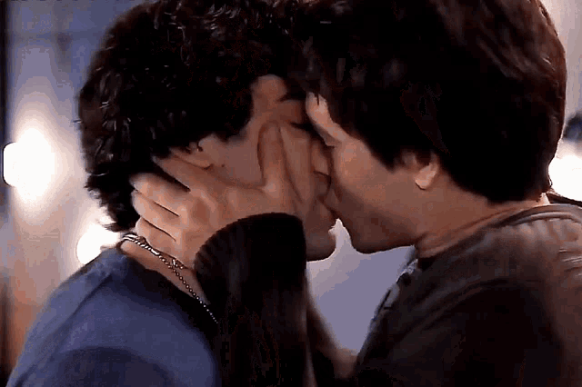 a couple of men are kissing each other on the forehead .