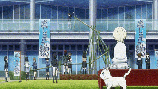 a group of people are standing in front of a building and a cat is sitting on a table in front of them .