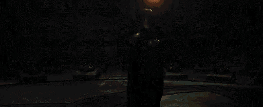 a man is standing in front of a fire in a dark room .