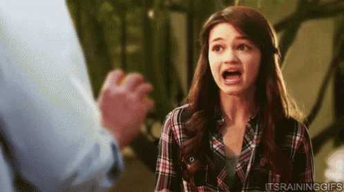 a woman in a plaid shirt is making a funny face while a man holds her hand .