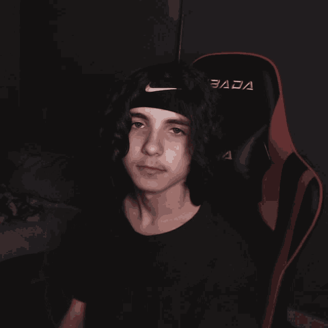 a young man wearing a nike headband sits in a chair that says fada