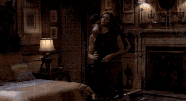 a woman in a black dress is standing in a dark bedroom