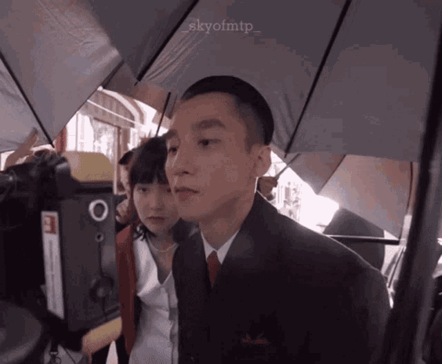 a man in a suit and tie is standing next to a woman under an umbrella with the hashtag skyofmtp_