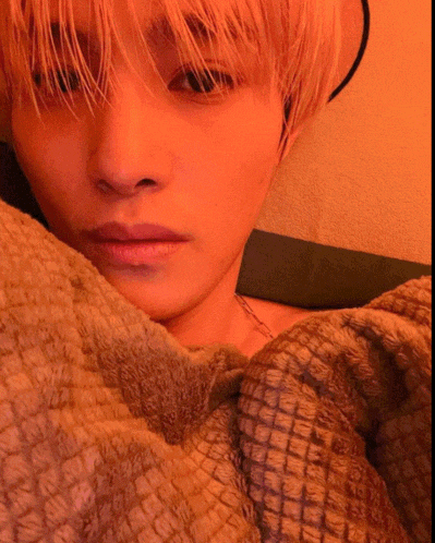 a close up of a person laying on a bed with a blanket