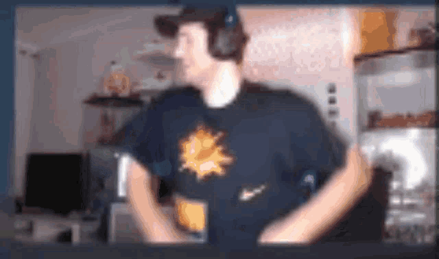 a man wearing headphones and a t-shirt with a sun on it is dancing in a room .