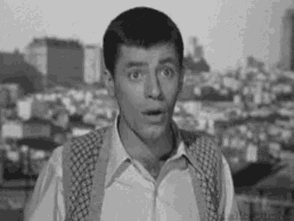 a black and white photo of a man wearing suspenders and a white shirt .