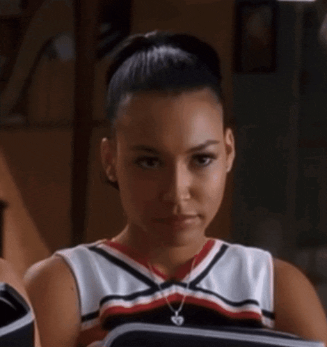 a woman in a cheerleader outfit is holding a book and looking at it .
