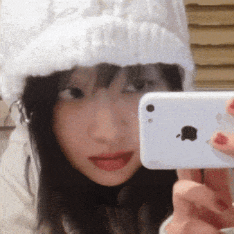 a woman wearing a white hat takes a picture of herself with an apple phone
