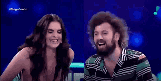 a man and a woman are laughing together in front of a mega senha sign