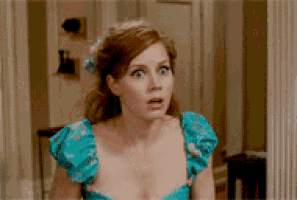 a woman in a blue dress looks surprised in front of a mirror