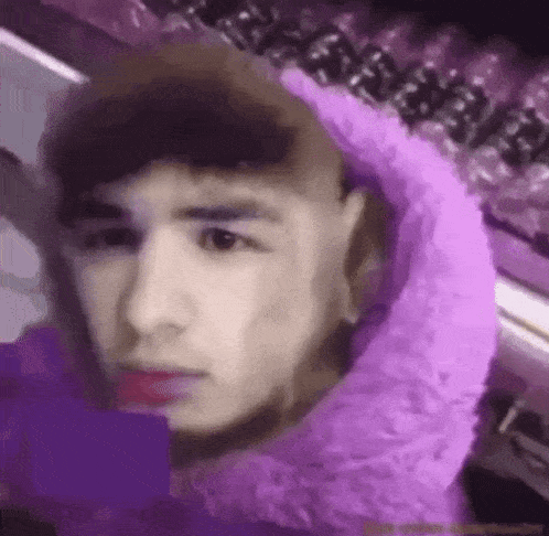 a man is wearing a purple hoodie and taking a picture of himself .