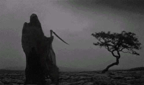 the grim reaper is holding a scythe and standing in front of a tree in a black and white photo .