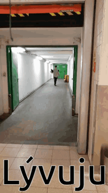 a man is walking down a hallway with the word lyvuju written on the bottom