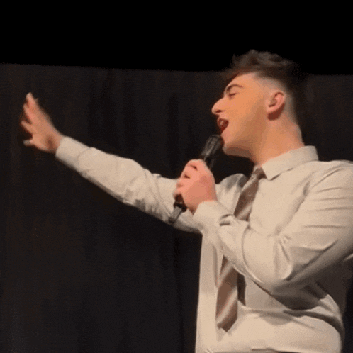a man singing into a microphone with his arm outstretched