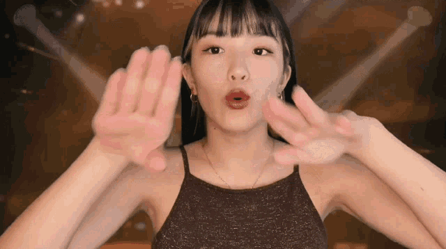 a woman in a halter top is making a funny face with her hands