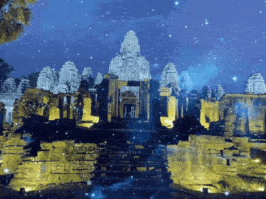 a temple is lit up at night with a blue sky behind it