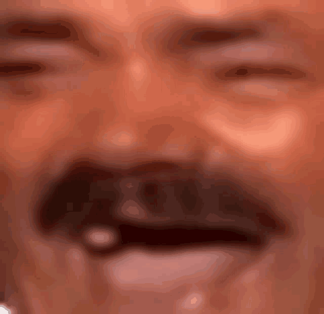 a close up of a man with a mustache laughing .