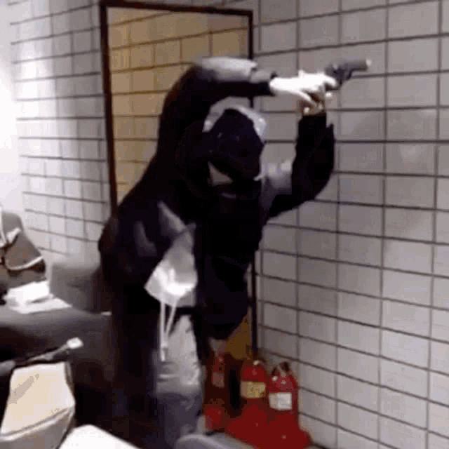 a man is holding a gun in front of a white tile wall .
