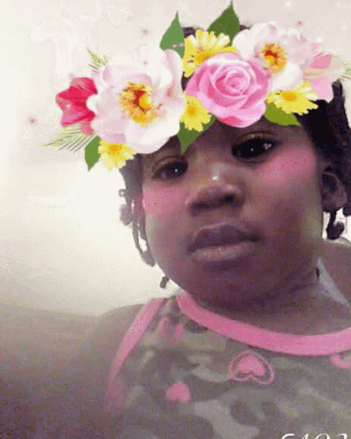 a girl with a flower crown on her head is wearing a pink shirt with a heart on it