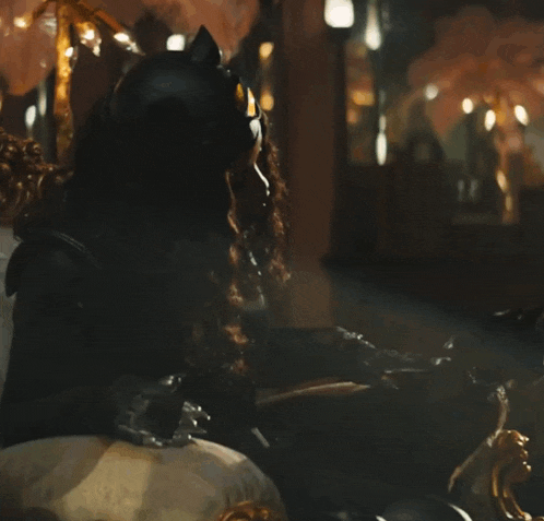 a woman in a black cat costume is sitting in a chair