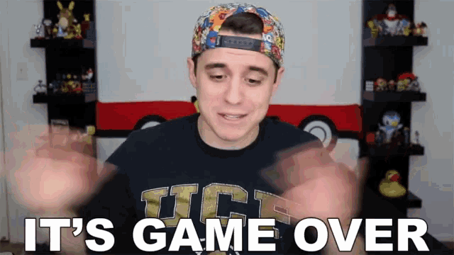 a man wearing a hat and a tct shirt is saying it 's game over