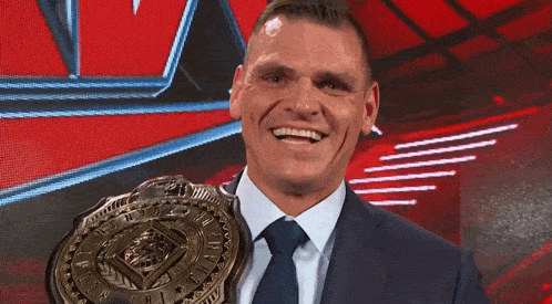 a man in a suit and tie is holding a championship belt and smiling