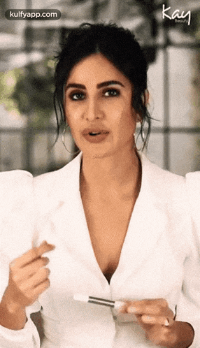 katrina kaif is wearing a white jacket and holding a brush in her hand
