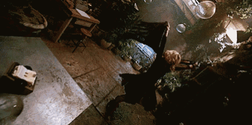 a woman is dancing in a dark room with plants