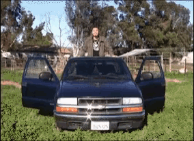 a man stands on the hood of a chevrolet blazer with the doors open