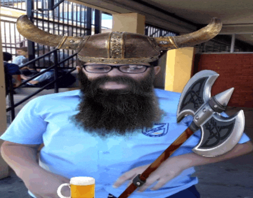 a man with a beard wearing a viking helmet and holding a beer mug