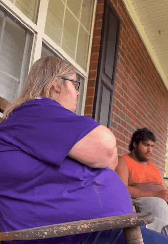 a woman in a purple shirt sits next to a man in an orange shirt on a porch