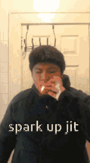 a man in a black jacket is smoking a cigarette with the words spark up jit written on the bottom