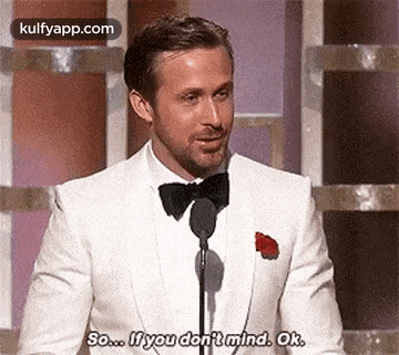 a man in a white suit and bow tie is giving a speech at a podium .
