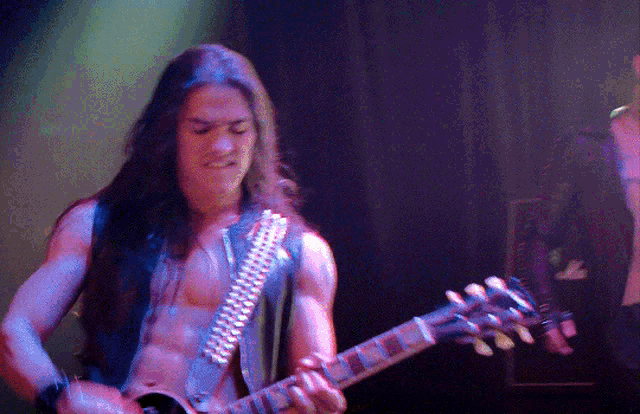 a man without a shirt is playing a guitar