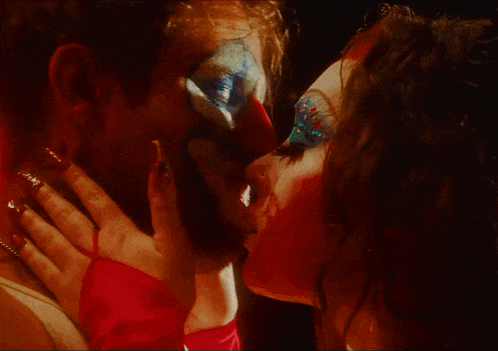 a man and a woman kissing with a clown face painted on their faces