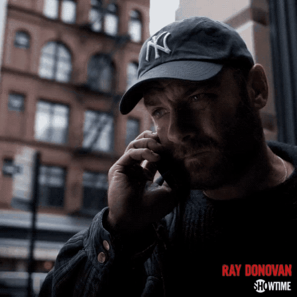 a man wearing a new york yankees hat is talking on a phone